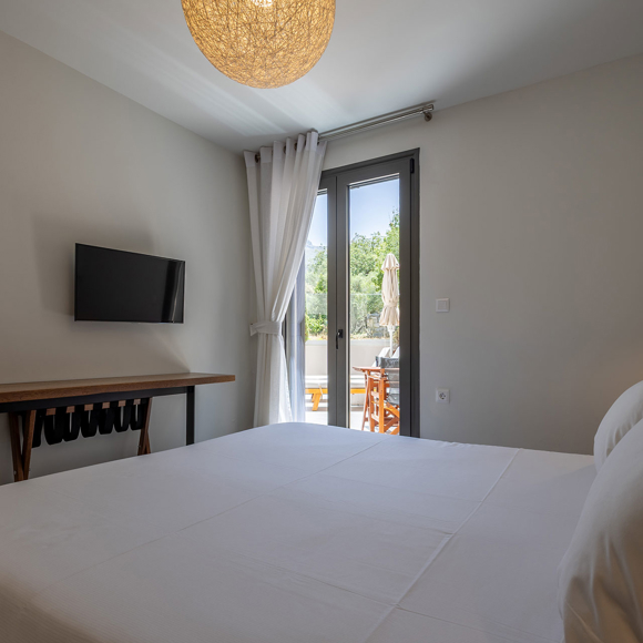 Suite modern bedroom with king bed, TV and access to outdoor terrace at Avdou Collection Crete