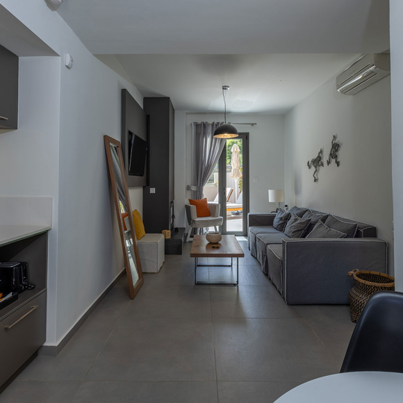 Suite's modern open plan living room with kitchen area and seating with access to outdoor terrace at Avdou Collection