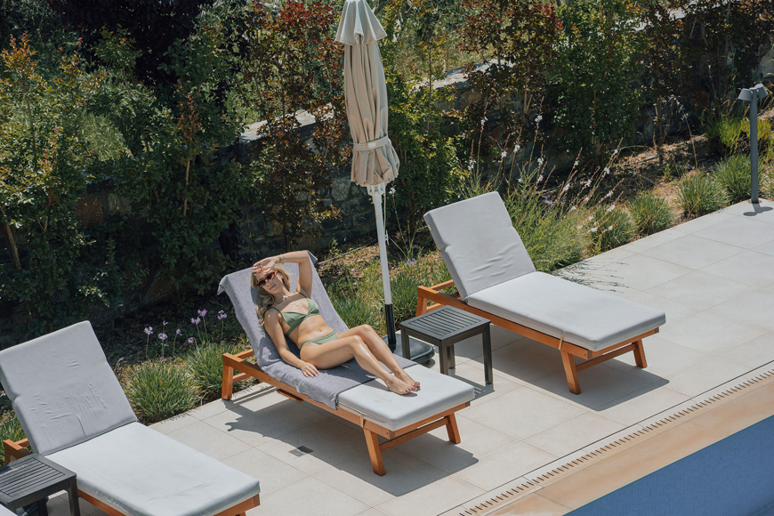 Guest enjoying the sun on a poolside lounger surrounded by greenery at Avdou Collection Crete