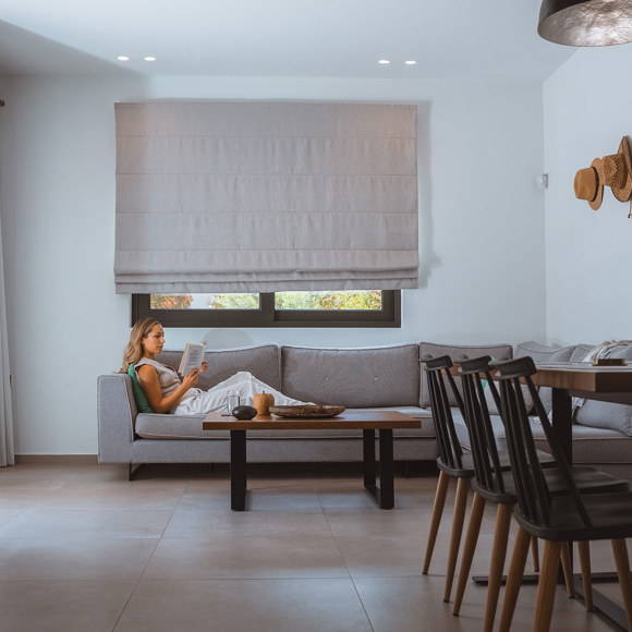 Guest relaxing with a book in the bright living room of a modern villa at Avdou Collection Crete