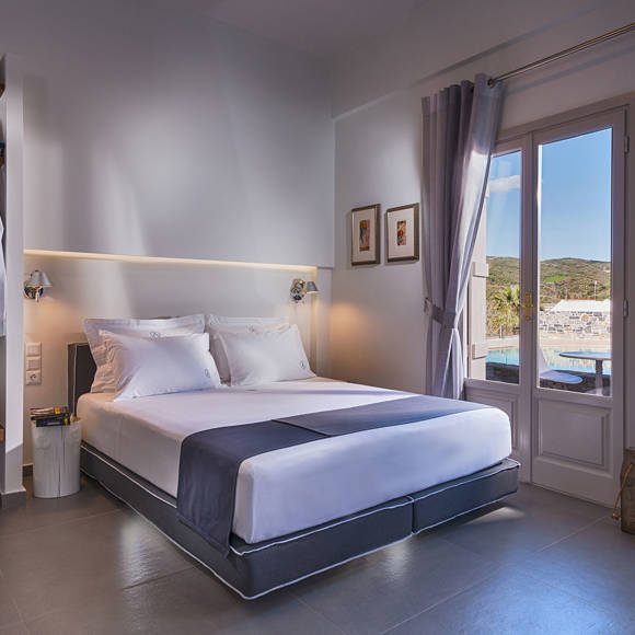 Open plan suite with large bed, open wardrobe and a window with view at Avdou Collection Crete