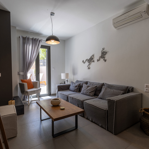 Suite with modern open living space with sofa, chair, coffee table and access to outdoor terrace at Avdou Collection