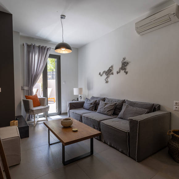 Suite with modern open living space with sofa, chair, coffee table and access to outdoor terrace at Avdou Collection