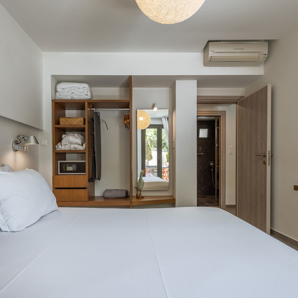 Suite's bright bedroom with double bed and open wardrobe with large mirror at Avdou Collection Crete