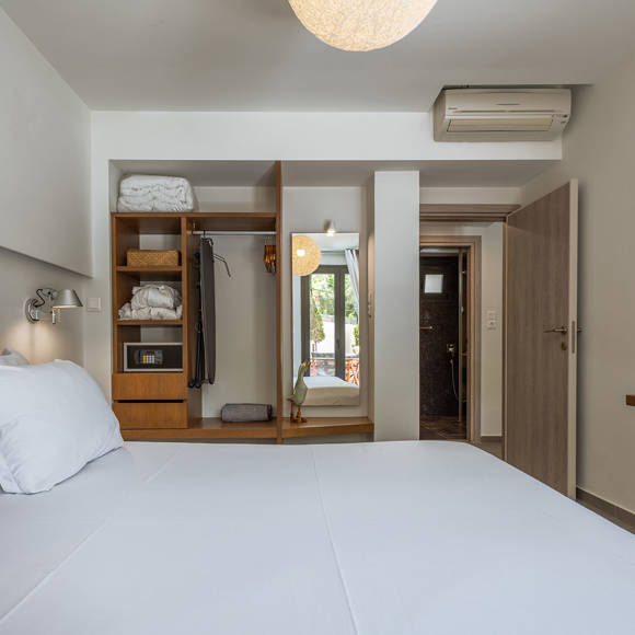 Suite's bright bedroom with double bed and open wardrobe with large mirror at Avdou Collection Crete