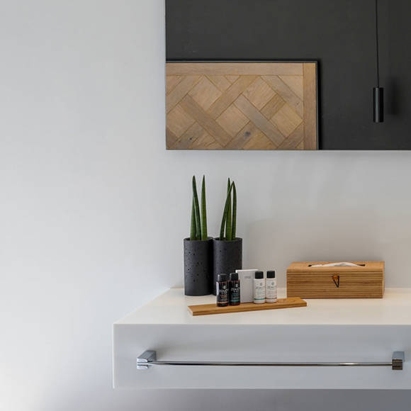 Minimal bathroom counter with fresh towels, amenities, plants and wooden accents in the two bedroom grand villa