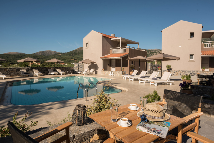 Relaxing poolside setting with sun loungers, umbrellas and mountain views at Avdou Collection Crete