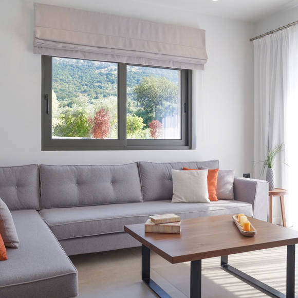 Spacious living room with corner sofa, colorful cushions and large window overlooking nature in the grand villa Avdou Collection