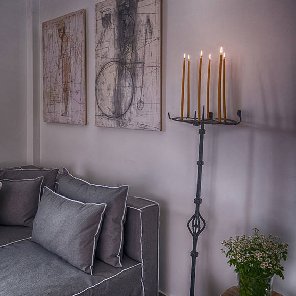 Cozy living room with gray couch, artwork on the wall and lit candle stand at Avdou Collection Crete