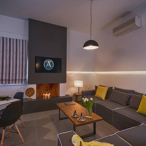 Open plan suite living room with fireplace, large sofa and dining area at Avdou Collection Crete