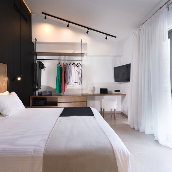 Grand villa master bedroom with king size bed, open wardrobe, work desk and terrace with sun loungers at Avdou Collection