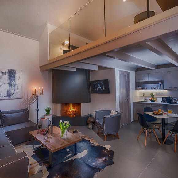 Modern, cozy living room with fireplace, sofa, dining area, artworks and loft area and kitchen at Avdou Collection