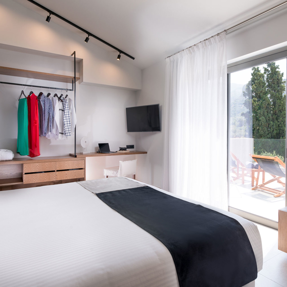 Master bedroom with dounle bed, open closet, work desk and balcony access in the two bedroom grand villa Avdou Collection