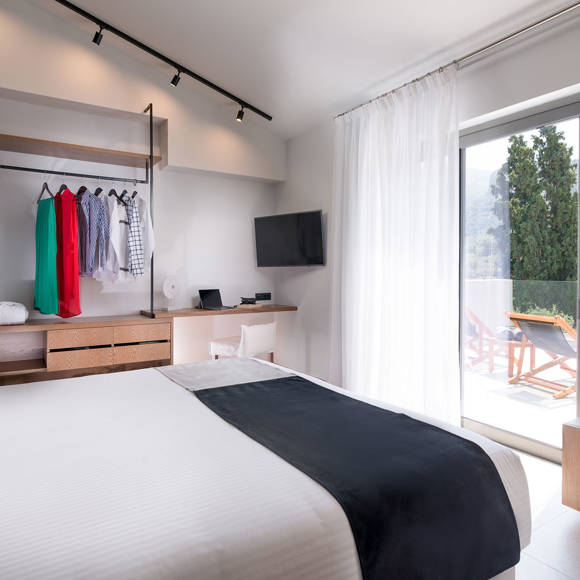 Master bedroom with dounle bed, open closet, work desk and balcony access in the two bedroom grand villa Avdou Collection