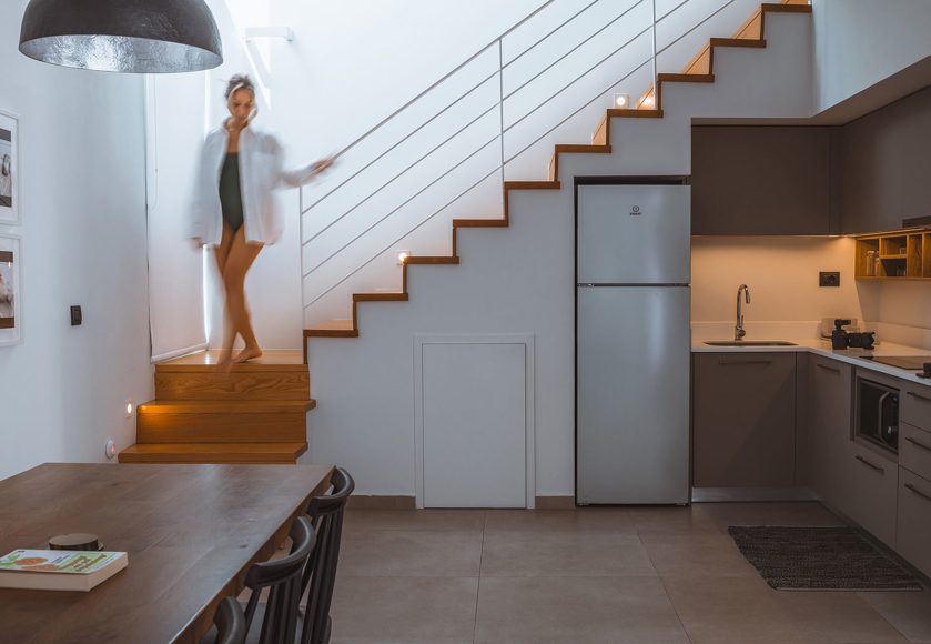 Modern villa kitchen and dining area with wooden stairs and soft lighting at Avdou Collection Crete