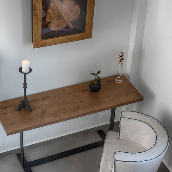 Modern interior design of a suite with wooden console table, framed art, candle holder and chair at Avdou Collection