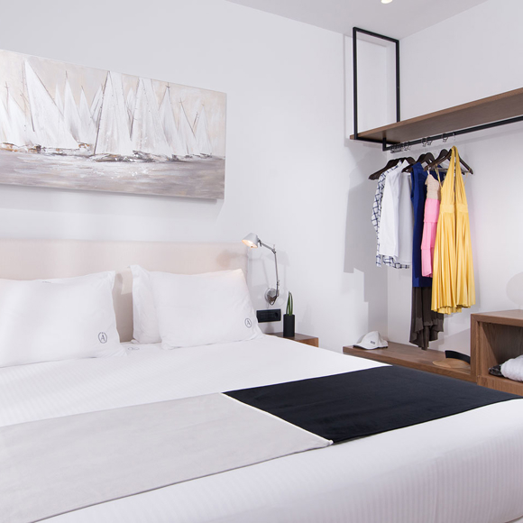 Three bedroom grand villa with double bed, open wardrobe with clothes and desk with chair at Avdou Collection Crete