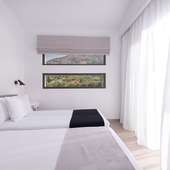 Three bedroom grand villa with twin beds placed by large windows with views of the Cretan hills and soft light