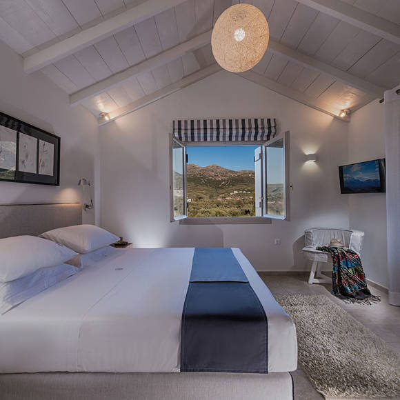 Junior villa bedroom with king size bed, open window with mountain view, TV and cozy decor at Avdou Collection