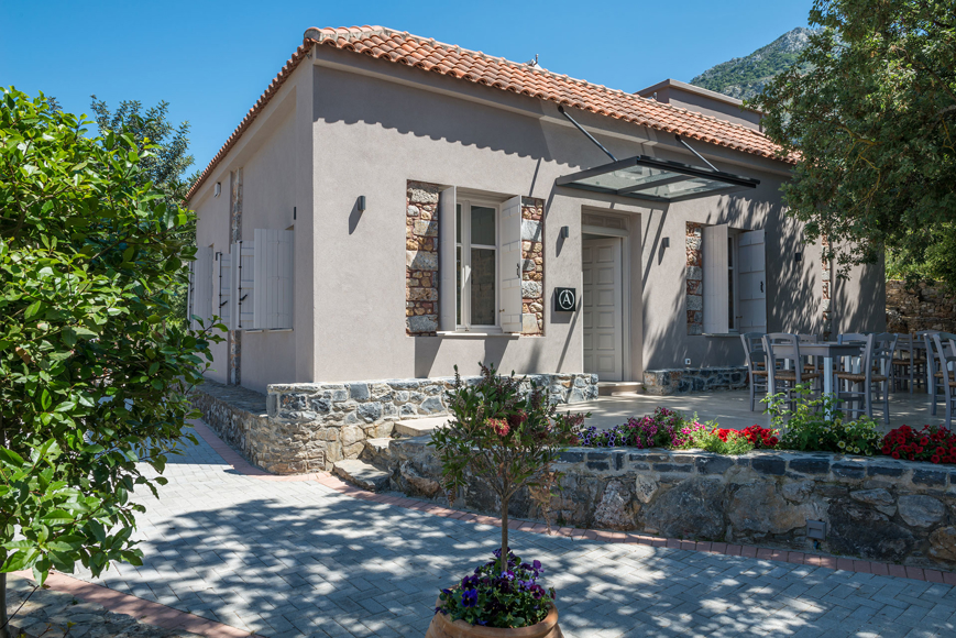 Charming cafe restaurant with stone details, outdoor seating and colorful flowers at Avdou Collection Crete