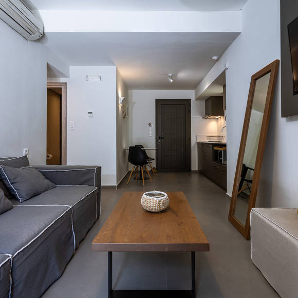 Suite modern living space with gray couch, wooden furniture and kitchen area at Avdou Collection Crete